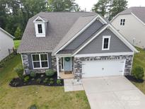 Charming home featuring stone accents, gray siding, and a well-manicured front yard at 16112 Langston Dr, Charlotte, NC 28278