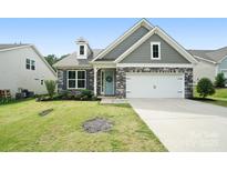 Charming home featuring a stone and gray siding facade with a two-car garage and a well-manicured lawn at 16112 Langston Dr, Charlotte, NC 28278