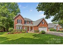 Charming brick home with manicured lawn, two-car garage, and inviting front porch seating area at 1624 Moonstone Dr, Matthews, NC 28105