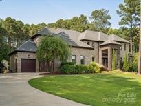 Stately brick home with a well-manicured lawn, mature trees, and a curved driveway leading to a two-car garage at 172 Barber Loop, Mooresville, NC 28117