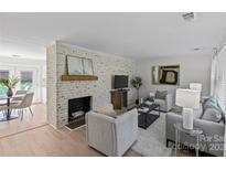 Bright living room featuring a brick fireplace, light wood floors, and neutral-toned furnishings at 5329 Valley Forge Rd, Charlotte, NC 28210