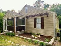Charming home featuring tan siding, a screened porch, a decorative pergola, and a landscaped garden bed at 659 Annafrel St, Rock Hill, SC 29730