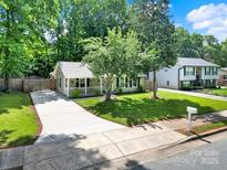 Charming single-story home with a well-manicured lawn, a long driveway, and mature trees at 6705 Reddman Rd, Charlotte, NC 28212
