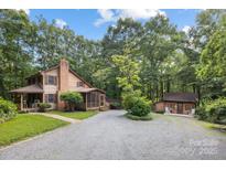Charming two-story wood home nestled amongst mature trees with a circular gravel driveway and guesthouse at 715 White Oaks Cir, Monroe, NC 28110