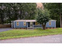 Charming single-story home with blue siding, a metal roof, and a well-manicured lawn surrounded by mature trees at 870 Family Dr, Midland, NC 28107