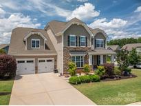 Charming two-story home featuring a two-car garage, stone accents, and manicured landscaping at 104 Wingstem Ct, Mooresville, NC 28117