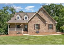 Charming brick home featuring a covered porch and manicured lawn at 135 Oak Creek Dr, Rockwell, NC 28138