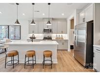 Bright kitchen features a large island with seating, stainless steel appliances, and grey cabinets at 223 Halemarg Dr, Belmont, NC 28012