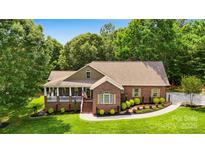 Charming brick home featuring a landscaped front yard, covered porch, and well-manicured shrubbery at 234 Rivercliff Dr, Stony Point, NC 28678
