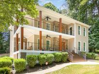 Stunning two-story home boasts a double porch with wooden pillars and stone accents on a tree-lined lot at 345 Beaten Path Rd, Mooresville, NC 28117