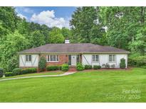 Charming single-story home with a brick and white facade, lush lawn, and mature trees providing privacy at 3504 Mountainbrook Rd, Charlotte, NC 28210