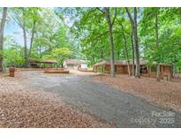 Charming brick home with a long driveway, lush trees, and a separate garage at 3985 Well Rd, Mint Hill, NC 28227