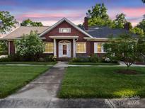 Charming brick home featuring manicured lawn, inviting front porch, and blossoming trees at 729 Montgomery Ave, Albemarle, NC 28001