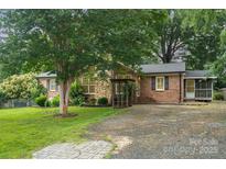 Charming brick home with lush landscaping, mature trees, and a welcoming stone-accented entrance at 7613 Happy Hollow Dr, Mint Hill, NC 28227