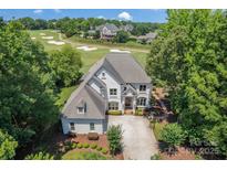 Stunning exterior elevation of home overlooking a golf course and showcases the well-maintained landscape at 1032 Spyglass Ln, Waxhaw, NC 28173
