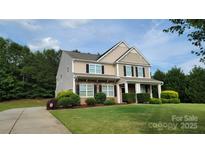 Beautiful two-story home with a well-manicured lawn and a charming front porch at 11922 Kimberfield Rd, Matthews, NC 28105