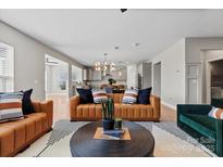 Open-concept living room featuring stylish leather furniture and a view of the kitchen and dining area at 12205 Hollinhope Dr, Charlotte, NC 28278