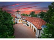 Stunning sunset view of a luxury estate featuring an elegant circular driveway and clay tile roof at 173 Rehoboth Ln, Mooresville, NC 28117