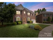 Charming two-story brick home with manicured lawn and mature trees at twilight at 1830 Alden Oaks Ln, Charlotte, NC 28270