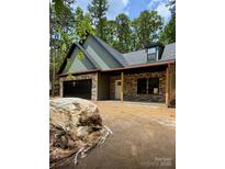 New construction featuring stone and green siding, a black garage door, and a charming front porch at 1923 Fairfield Rd, Mount Gilead, NC 27306