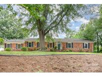Charming brick home featuring lush landscaping, mature trees and a welcoming entrance at 1925 Montclair Ave, Gastonia, NC 28054