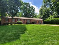 Charming brick ranch home featuring a lush lawn and mature trees in a desirable neighborhood at 2104 Farmbrook Dr, Statesville, NC 28625