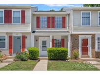 Charming townhome with a well-manicured front yard and inviting entrance. Features red shutters at 218 Water Oak Dr, Pineville, NC 28134
