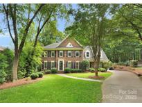 Beautiful two-story brick home featuring manicured lawn, mature trees, and welcoming front entrance at 2432 Hartmill Ct, Charlotte, NC 28226
