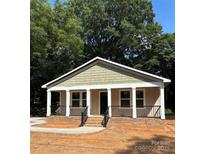 Charming single-story home with a welcoming front porch and brick foundation, nestled among mature trees at 307 Wilson St, Monroe, NC 28112