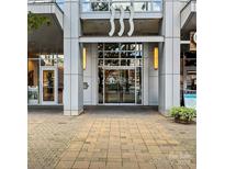 Modern building entrance featuring glass doors, white columns, and sleek architectural details at 333 W Trade St # 1106, Charlotte, NC 28202