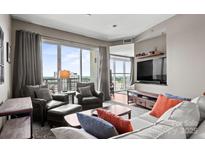 Comfortable living room featuring large windows with city views, a sectional sofa, and contemporary furnishings at 333 W Trade St # 1106, Charlotte, NC 28202