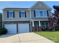 Charming two-story home features a two-car garage, stone accents, and a cozy front porch seating area at 4151 Granite St, Midland, NC 28107