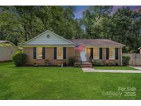 Charming brick home with a well-manicured lawn and an American flag waving in the breeze at 6215 Cross Creek Ln, Charlotte, NC 28212