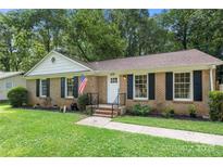 Charming brick home featuring a well-manicured lawn, black shutters, and an American flag at 6215 Cross Creek Ln, Charlotte, NC 28212