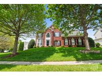 Charming two-story brick home with lush front yard and mature trees, creating a welcoming curb appeal at 6803 Augustine Way, Charlotte, NC 28270