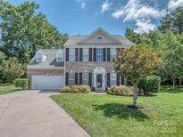 Charming two-story brick home with well-manicured lawn and black shutters, complemented by mature trees at 7700 Antique Cir, Waxhaw, NC 28173