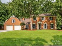 Charming two-story brick home with attached garage and mature trees on a lush green lawn at 113 Foxfield Ln, Matthews, NC 28105