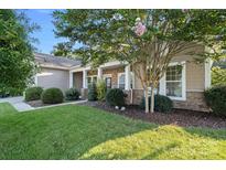 Charming single-story home featuring a stone facade, well-manicured lawn, and mature trees on a sunny day at 114 Canoe Pole Ln, Mooresville, NC 28117
