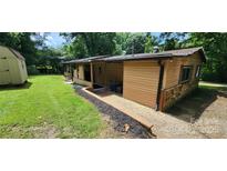 Charming home exterior showcasing the landscaped yard, wood paneling and stone foundation at 121 C And C Ln, Mooresville, NC 28115