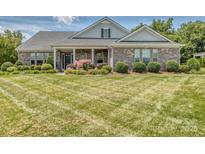 Charming brick home featuring manicured landscaping and a well-maintained, expansive front lawn at 314 Candella Dr, Matthews, NC 28104