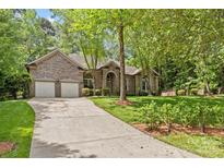 Charming brick home featuring a well-manicured lawn and a long driveway leading to an attached two-car garage at 4025 Cherrybrook Dr, Mint Hill, NC 28227