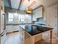 Modern kitchen features stainless appliances, black counters, a center island, and a beautiful hanging light fixture at 4121 Selwyn Walk Ct, Charlotte, NC 28209