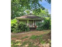 Charming red and white exterior with a covered porch surrounded by lush greenery at 423 Tot Dellinger Rd, Cherryville, NC 28021