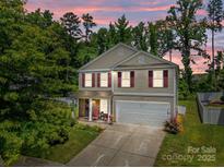 Charming two-story home with red shutters, lush landscaping and an inviting covered porch, perfect for relaxing evenings at 5009 Granite Creek Ln, Charlotte, NC 28269