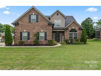 Charming brick home features a well-manicured lawn and lovely landscaping with mature trees and bushes at 5379 Roberta Meadows Ct, Concord, NC 28027