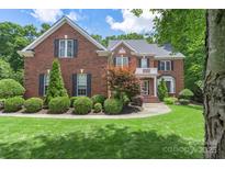 Beautiful two-story red brick home featuring a manicured lawn, mature trees, and classic architectural details at 6006 Casswell Cir, Matthews, NC 28104