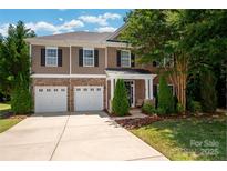 Charming two-story home featuring a two-car garage, manicured lawn, and a welcoming front porch at 8909 Savannah Rd, Harrisburg, NC 28075