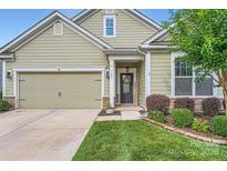 Charming home featuring a welcoming front porch, well-manicured lawn, and an attached garage, creating curb appeal at 125 Rosebay Dr, Mooresville, NC 28117