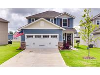 Charming two-story home with a two car garage, stone accents, landscaped lawn, and an American flag at 150 Bezelle Ave, York, SC 29745