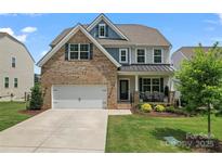 Charming two-story home featuring a brick facade, attached garage, manicured lawn and covered porch, located in a desirable neighborhood at 17231 Rider Wood Ln, Charlotte, NC 28278
